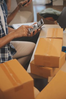 İki Asyalı blogcu, dükkanında canlı yayın yapan videoyu kaydetmek için kameranın önünde kıyafetlerini gösteriyor. Çevrimiçi alışveriş arabası fikri. Evdeki kanepede.
