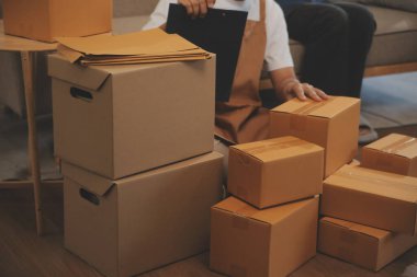 İki Asyalı blogcu, dükkanında canlı yayın yapan videoyu kaydetmek için kameranın önünde kıyafetlerini gösteriyor. Çevrimiçi alışveriş arabası fikri. Evdeki kanepede.