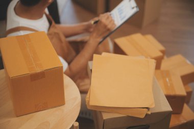 İki Asyalı blogcu, dükkanında canlı yayın yapan videoyu kaydetmek için kameranın önünde kıyafetlerini gösteriyor. Çevrimiçi alışveriş arabası fikri. Evdeki kanepede.