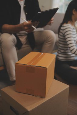 İki Asyalı blogcu, dükkanında canlı yayın yapan videoyu kaydetmek için kameranın önünde kıyafetlerini gösteriyor. Çevrimiçi alışveriş arabası fikri. Evdeki kanepede.