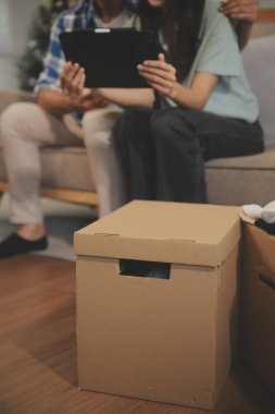 İki Asyalı blogcu, dükkanında canlı yayın yapan videoyu kaydetmek için kameranın önünde kıyafetlerini gösteriyor. Çevrimiçi alışveriş arabası fikri. Evdeki kanepede.