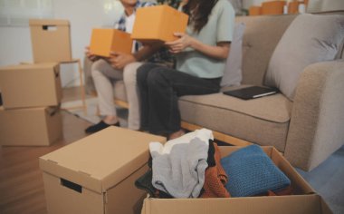 İki Asyalı blogcu, dükkanında canlı yayın yapan videoyu kaydetmek için kameranın önünde kıyafetlerini gösteriyor. Çevrimiçi alışveriş arabası fikri. Evdeki kanepede.