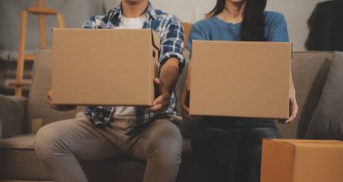 İki Asyalı blogcu, dükkanında canlı yayın yapan videoyu kaydetmek için kameranın önünde kıyafetlerini gösteriyor. Çevrimiçi alışveriş arabası fikri. Evdeki kanepede.