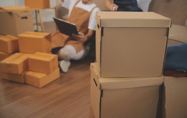 İki Asyalı blogcu, dükkanında canlı yayın yapan videoyu kaydetmek için kameranın önünde kıyafetlerini gösteriyor. Çevrimiçi alışveriş arabası fikri. Evdeki kanepede.