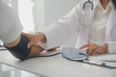 Erkek doktor, check-up, tıbbi tedavi ve sağlık konsepti için hastaneye gelen hastaların vücut basıncını ve nabzını ölçmek için kan basıncı monitörü kullanır..