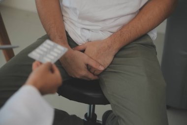 Erkek hastalıkları. Adam ellerini kasıklarına bastırıyor ve acı çekiyor. Panorama, kesilmiş, stüdyo çekimi.