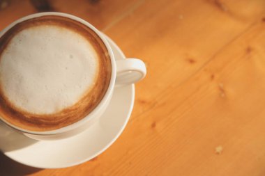 Tahta masada, beyaz fincanda kaşık ile kahve..