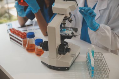 Coronavirus aşısı geliştirmek için mikroskop ile çalışan biyokimyasal araştırma ekibi farmasötik araştırma laboratuvarında, seçici odaklı