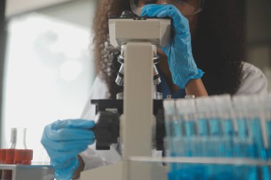 Coronavirus aşısı geliştirmek için mikroskop ile çalışan biyokimyasal araştırma ekibi farmasötik araştırma laboratuvarında, seçici odaklı