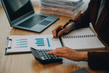 Asyalı iş kadını dizüstü bilgisayar kullanıyor ve ofiste hesap makinesi ile çalışıyor, mali raporu, iş planı yatırımını, mali analiz konseptini analiz etmeyi planlıyor..