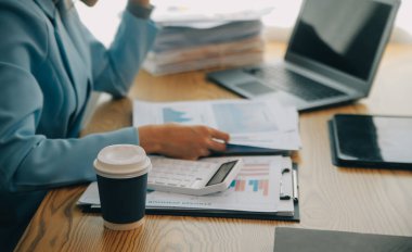 Asyalı iş kadını dizüstü bilgisayar kullanıyor ve ofiste hesap makinesi ile çalışıyor, mali raporu, iş planı yatırımını, mali analiz konseptini analiz etmeyi planlıyor..