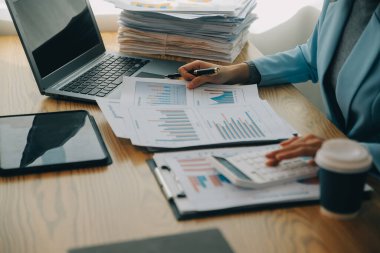 Asyalı iş kadını dizüstü bilgisayar kullanıyor ve ofiste hesap makinesi ile çalışıyor, mali raporu, iş planı yatırımını, mali analiz konseptini analiz etmeyi planlıyor..