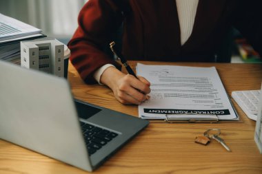 Emlakçı ve müşteri satın alma, sigorta ya da kredi alma ya da emlak ya da mülkiyet sözleşmesi hakkında tartışıyorlar.