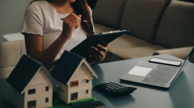 Emlakçı müşterilere örnek evler, ipotekli kredi sözleşmeleri veriyor. Kiralık bir ev alıp satmak için bir sözleşme yap. ve ev sigortası sözleşmeleri, ev kredisi konseptleri