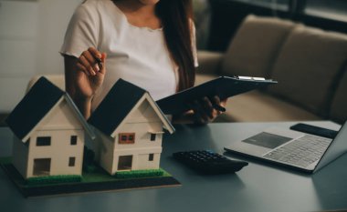 Emlakçı müşterilere örnek evler, ipotekli kredi sözleşmeleri veriyor. Kiralık bir ev alıp satmak için bir sözleşme yap. ve ev sigortası sözleşmeleri, ev kredisi konseptleri