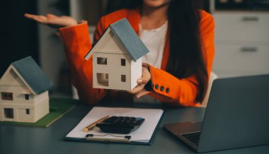 Emlakçı müşterilere örnek evler, ipotekli kredi sözleşmeleri veriyor. Kiralık bir ev alıp satmak için bir sözleşme yap. ve ev sigortası sözleşmeleri, ev kredisi konseptleri