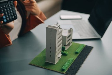 Yakın mesafede emlakçı, küçük ev modelini ve kır evinin planını tutuyor. Gayrimenkul alımı, yeni mülk, mülkiyet, inşaat şirketi müşteriye özel teklifte bulundu, uygun fiyatlı konut kavramı