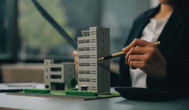 Yakın mesafede emlakçı, küçük ev modelini ve kır evinin planını tutuyor. Gayrimenkul alımı, yeni mülk, mülkiyet, inşaat şirketi müşteriye özel teklifte bulundu, uygun fiyatlı konut kavramı