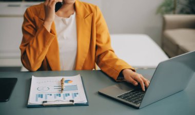 Ofisteki resmi takım elbiseli Asyalı iş kadını akıllı telefon ve çalışma süresince mutlu ve neşeli.