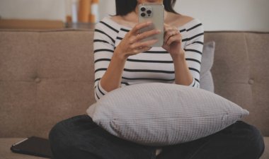 Mutluluk Girişimcisi güzel iş kadını Asyalı genç kadın online alışveriş için günlük kullanım cep telefonu takıyor. Ev ortamında sosyal medya ve dizüstü bilgisayarla iyi eğlenceler. İnternet bankacılığı.