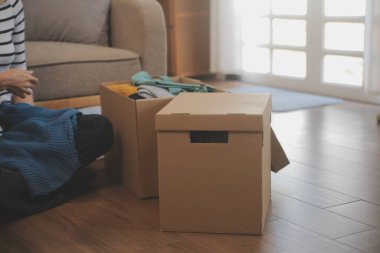 İki Asyalı blogcu, dükkanında canlı yayın yapan videoyu kaydetmek için kameranın önünde kıyafetlerini gösteriyor. Çevrimiçi alışveriş arabası fikri. Evdeki kanepede.