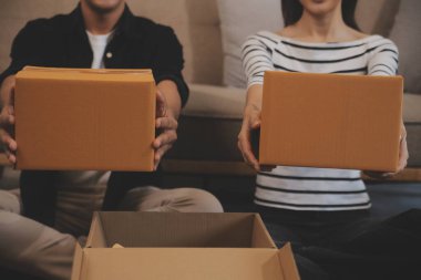 İki Asyalı blogcu, dükkanında canlı yayın yapan videoyu kaydetmek için kameranın önünde kıyafetlerini gösteriyor. Çevrimiçi alışveriş arabası fikri. Evdeki kanepede.