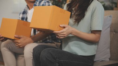 İki Asyalı blogcu, dükkanında canlı yayın yapan videoyu kaydetmek için kameranın önünde kıyafetlerini gösteriyor. Çevrimiçi alışveriş arabası fikri. Evdeki kanepede.