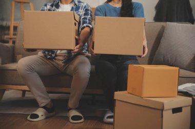 İki Asyalı blogcu, dükkanında canlı yayın yapan videoyu kaydetmek için kameranın önünde kıyafetlerini gösteriyor. Çevrimiçi alışveriş arabası fikri. Evdeki kanepede.