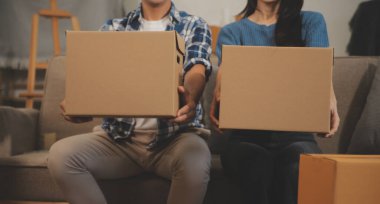 İki Asyalı blogcu, dükkanında canlı yayın yapan videoyu kaydetmek için kameranın önünde kıyafetlerini gösteriyor. Çevrimiçi alışveriş arabası fikri. Evdeki kanepede.