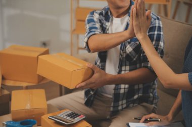 İki Asyalı blogcu, dükkanında canlı yayın yapan videoyu kaydetmek için kameranın önünde kıyafetlerini gösteriyor. Çevrimiçi alışveriş arabası fikri. Evdeki kanepede.