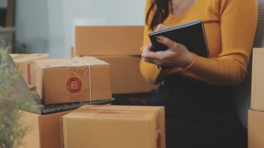 Odasındaki karton kutuların arasında genç bir Asyalı iş kadını, onun online satış ve nakliye işini temsil ediyor..