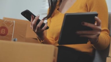 Odasındaki karton kutuların arasında genç bir Asyalı iş kadını, onun online satış ve nakliye işini temsil ediyor..