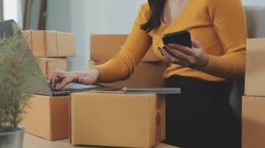 Odasındaki karton kutuların arasında genç bir Asyalı iş kadını, onun online satış ve nakliye işini temsil ediyor..