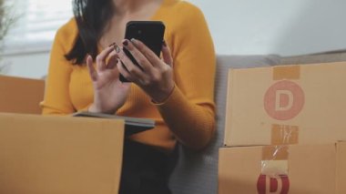 Odasındaki karton kutuların arasında genç bir Asyalı iş kadını, onun online satış ve nakliye işini temsil ediyor..