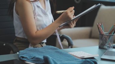 vlogger, blog yazarı küçük KOBİ iş kadını Asyalı güzel kadın kıyafetleri canlı yayın satışı internet üzerinden satışı, ana ofiste mevcut ürün detaylarını gösterme, girişimci ekommerce