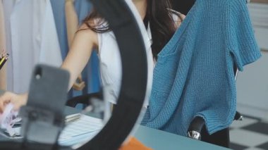 vlogger, blog yazarı küçük KOBİ iş kadını Asyalı güzel kadın kıyafetleri canlı yayın satışı internet üzerinden satışı, ana ofiste mevcut ürün detaylarını gösterme, girişimci ekommerce