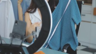 vlogger, blog yazarı küçük KOBİ iş kadını Asyalı güzel kadın kıyafetleri canlı yayın satışı internet üzerinden satışı, ana ofiste mevcut ürün detaylarını gösterme, girişimci ekommerce