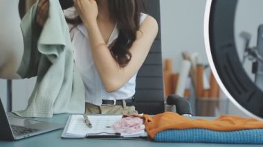 vlogger, blog yazarı küçük KOBİ iş kadını Asyalı güzel kadın kıyafetleri canlı yayın satışı internet üzerinden satışı, ana ofiste mevcut ürün detaylarını gösterme, girişimci ekommerce