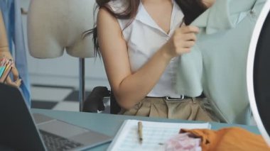 vlogger, blog yazarı küçük KOBİ iş kadını Asyalı güzel kadın kıyafetleri canlı yayın satışı internet üzerinden satışı, ana ofiste mevcut ürün detaylarını gösterme, girişimci ekommerce