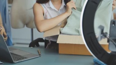 vlogger, blog yazarı küçük KOBİ iş kadını Asyalı güzel kadın kıyafetleri canlı yayın satışı internet üzerinden satışı, ana ofiste mevcut ürün detaylarını gösterme, girişimci ekommerce