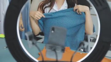 vlogger, blog yazarı küçük KOBİ iş kadını Asyalı güzel kadın kıyafetleri canlı yayın satışı internet üzerinden satışı, ana ofiste mevcut ürün detaylarını gösterme, girişimci ekommerce