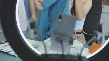 vlogger, blog yazarı küçük KOBİ iş kadını Asyalı güzel kadın kıyafetleri canlı yayın satışı internet üzerinden satışı, ana ofiste mevcut ürün detaylarını gösterme, girişimci ekommerce