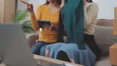 Genç bir kadın internetten alışveriş yapıyor ve oturma odasında kanepede otururken dizüstü bilgisayar kullanıyor..