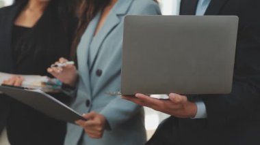 Bir grup genç iş adamı şık bir ofiste duruyor ve yeni proje, iş ve finans kavramını tartışıyorlar..