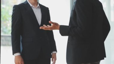 Bir grup genç iş adamı şık bir ofiste duruyor ve yeni proje, iş ve finans kavramını tartışıyorlar..