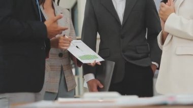 Bir grup genç iş adamı şık bir ofiste duruyor ve yeni proje, iş ve finans kavramını tartışıyorlar..