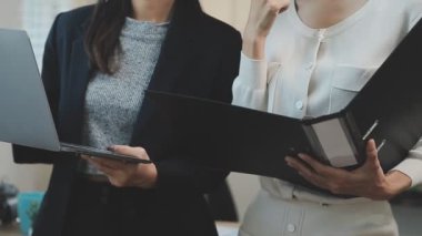 Finansal rapor üzerinde birlikte çalışan genç iş adamları şık bir ofiste iş ve finans temasını ön plana çıkarıyorlar..
