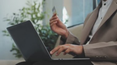 Ofiste laptopla ve kredi kartıyla çalışan işadamı