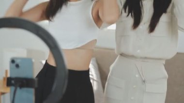 Evde kameranın önünde dans eden iki kadın.