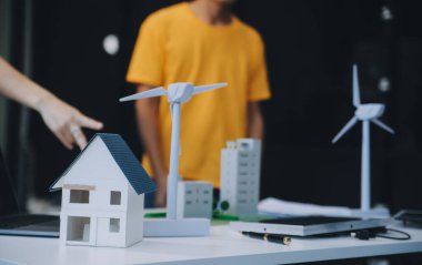 İki Genç Mühendis Güneş Hücresi Kurulum Toplantısı ve İş Tartışması Uzmanı. Ofis Odası 'nda Fabrika İnşaat Planlı Çatı Üzerine Güneş Fotovoltaik Panelleri Kurmayı Planlıyorum.